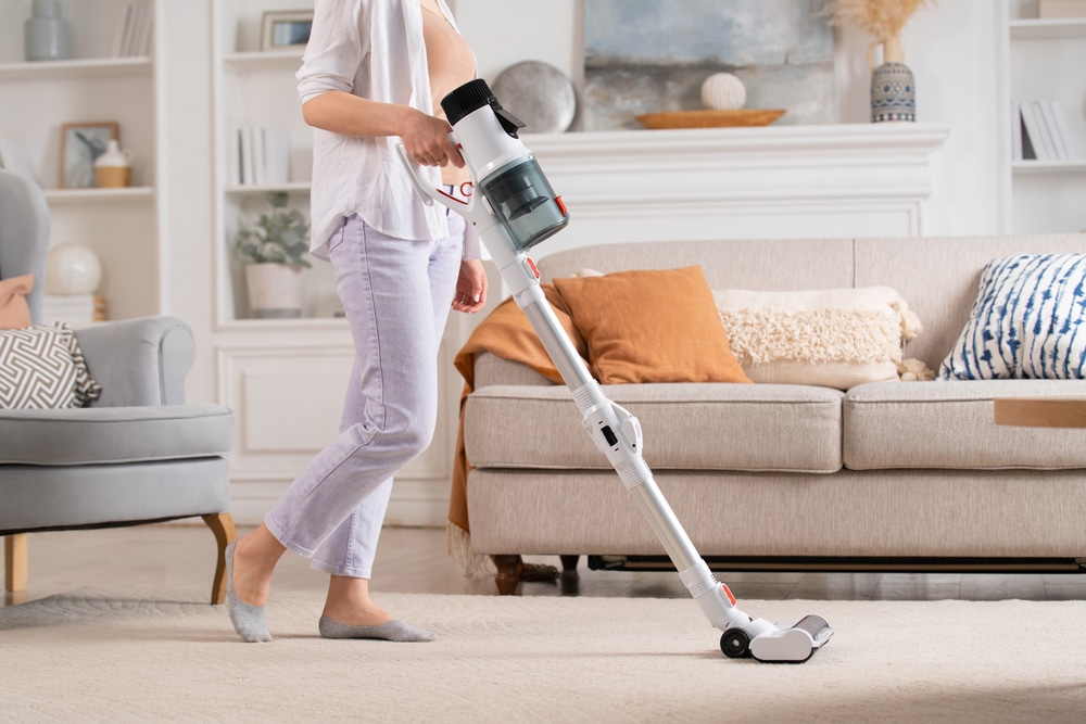 Young,Woman,Uses,Cordless,Vacuum,Cleaner,To,Clean,Home,Carpet