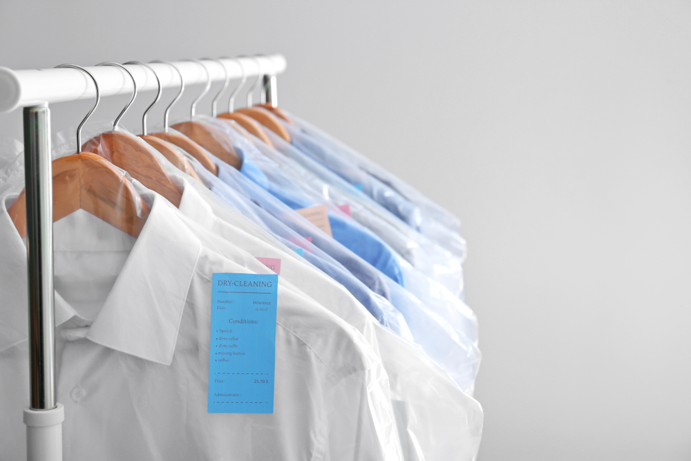 Rack with clean clothes on hangers after dry cleaning