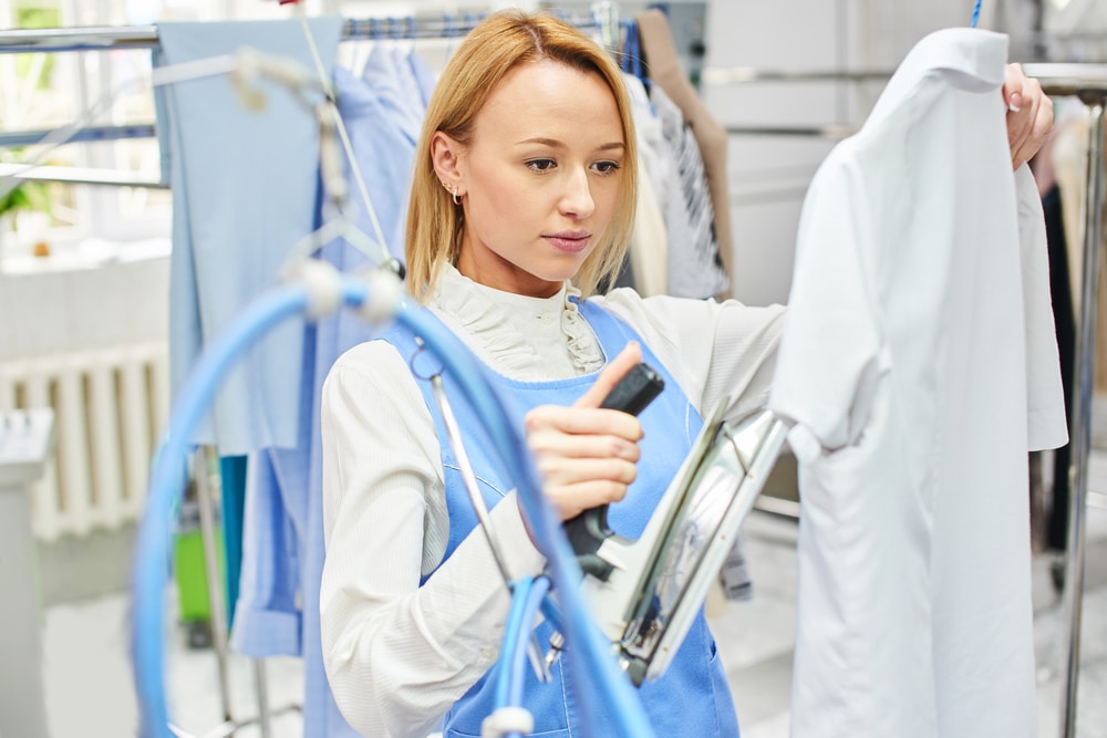 worker pats dry cleaning clothes at the dry cleaners iron