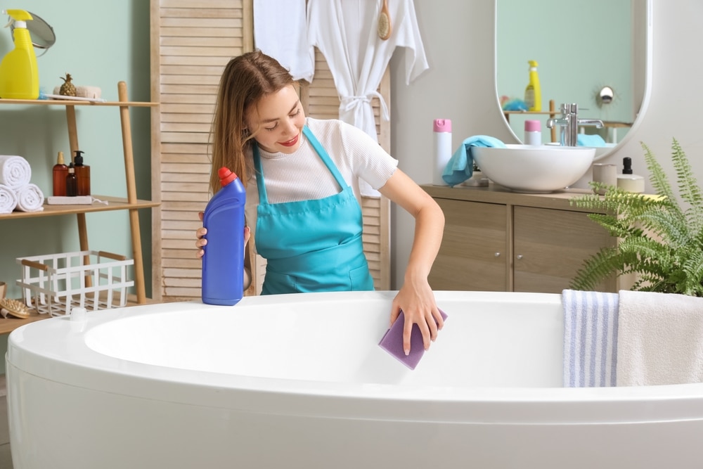 Young,Woman,Cleaning,Bathtub,With,Sponge,In,Bathroom